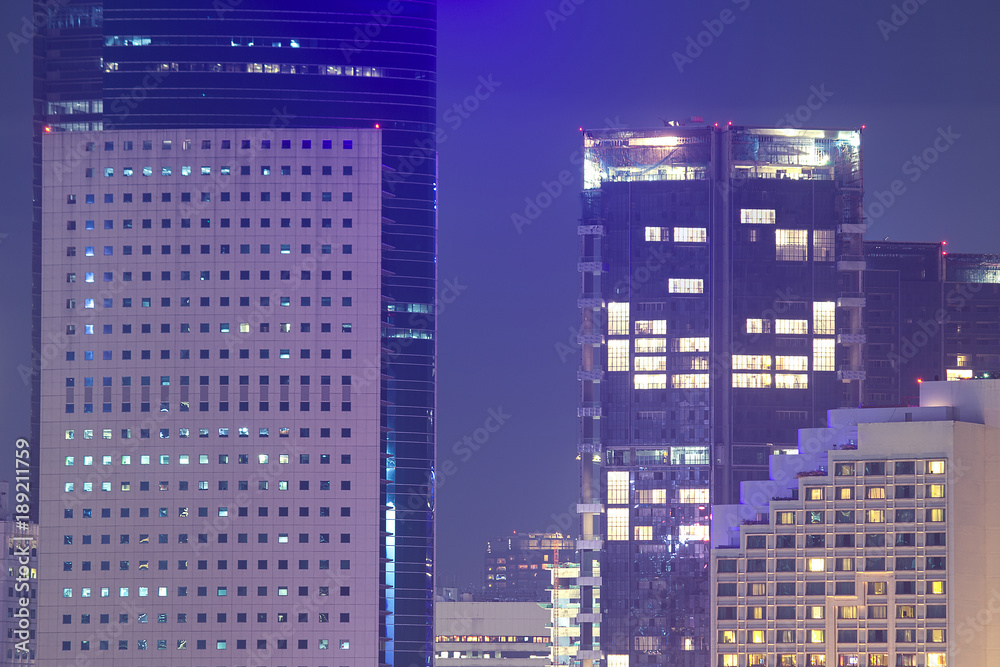 Priivacy concept in highrise apartment windows at night lit in cityscape urban highrise buildings.  Apartment towers for home property and rental.