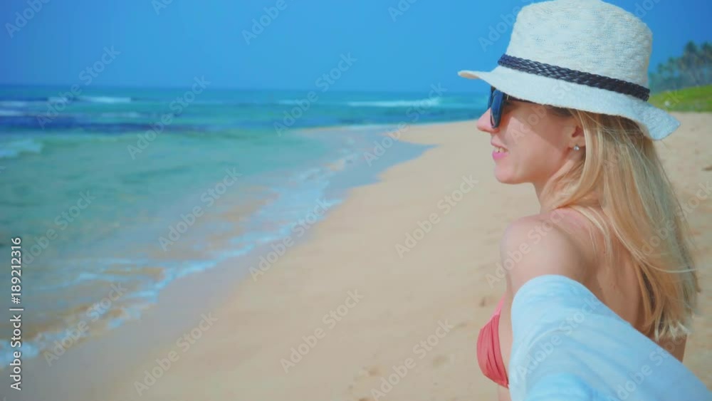 Woman wallking on the ocean beach under blue sky in sunny day. Seascape view with palms. Woman wallking on the ocean beach under blue sky in sunny day. Seascape view with palms.