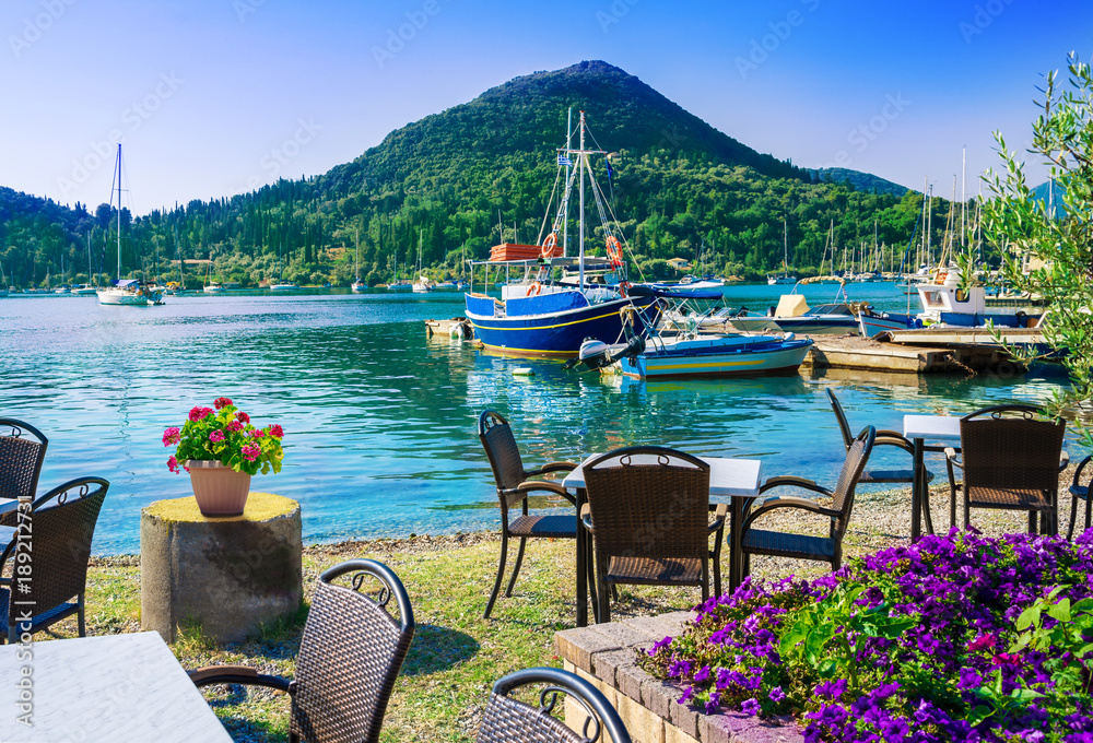 Terrace on the beach with flowers on table in Nydri village, harbour of Lefkada in Greece