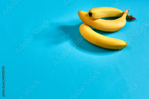 Fresh bananas close up on bright blue background. Flat lay. Summer concept.