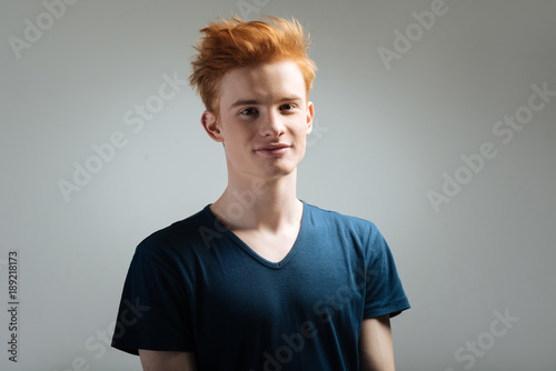 Happiness. Good-looking alert red-haired young man smiling and having a stylish haircut and wearing a black shirt