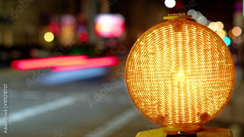 Construction site lamp at a construction site at night with flowing traffic in the background
