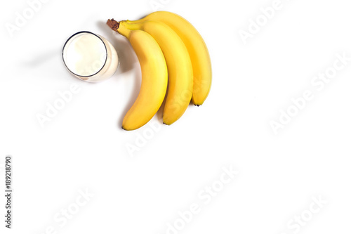 Glass of milk with bananas over white background. Top view