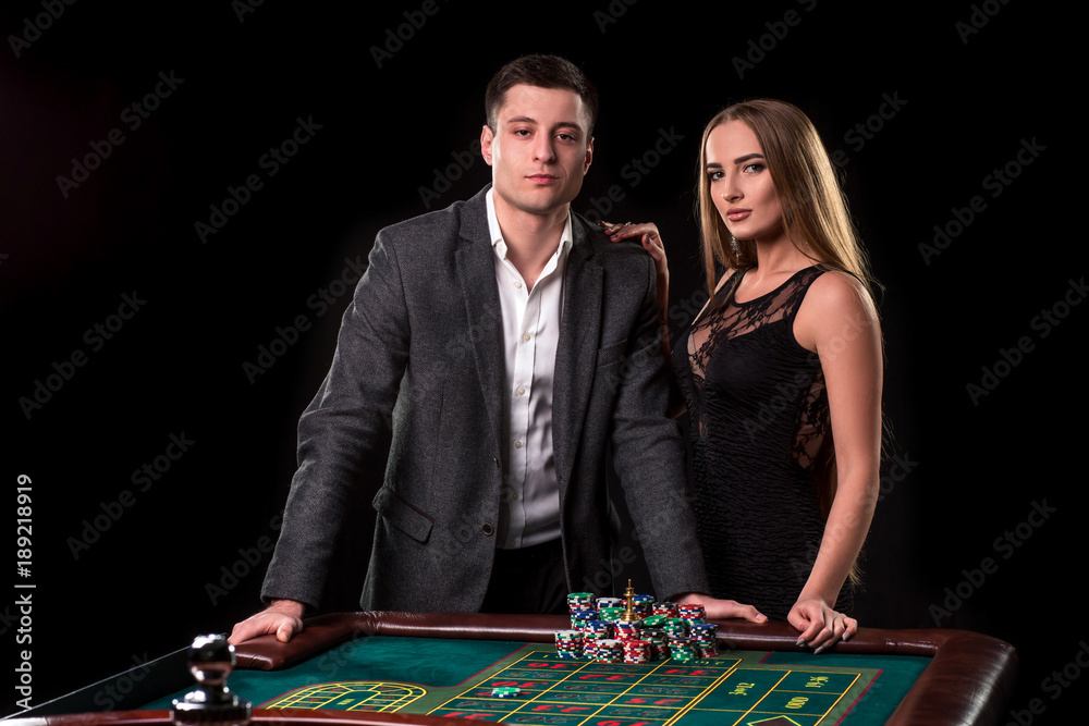 Elegant couple at the casino betting on the roulette, on a black background Elegant couple at the casino betting on the roulette, on a black background