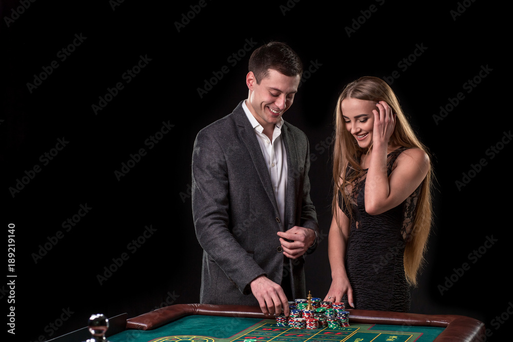 Elegant couple at the casino betting on the roulette, on a black background Elegant couple at the casino betting on the roulette, on a black background