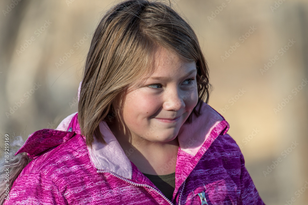 Cute girl smiling in a winter coat and blurred background