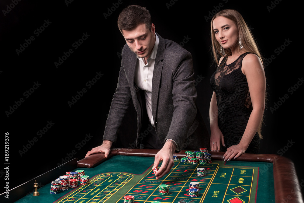 Elegant couple at the casino betting on the roulette, on a black background Elegant couple at the casino betting on the roulette, on a black background