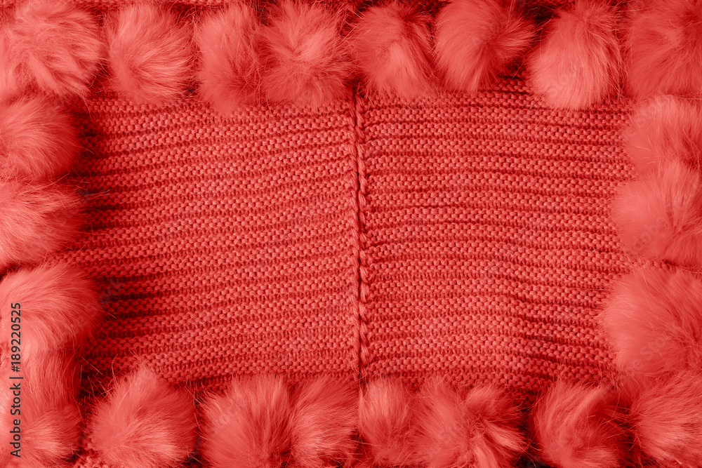 Red winter textile background with copy space and a frame with fluffy tassels