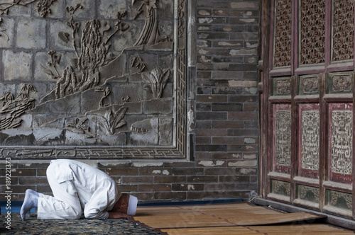 Fotografie One man praying at the Xi'An Great Mosque in the city of Xi'An in China, Asia