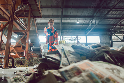 Woman in recycling center sweeping paper photo
