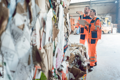 Workers in materials recovery facility in front of pressed paper
