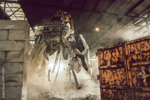 Grabber loading waste into container in recycling plant