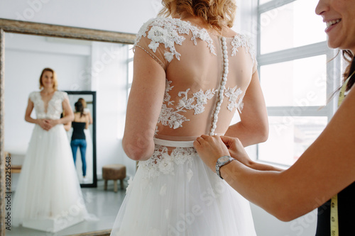 Fotografi Making final touch on tailor made gown in bridal shop