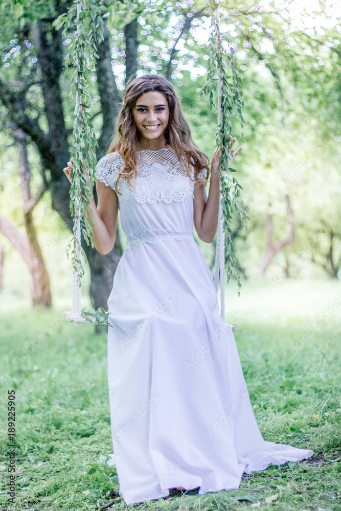Beautiful young girl sitting on the swing in a park and smiling. Beautiful young girl sitting on the swing in a park and smiling.