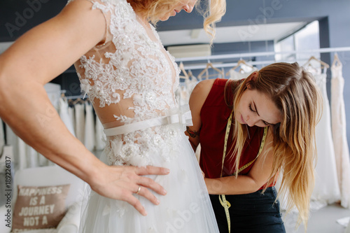 Schilderij op canvas Skillful designer fitting bridal gown to bride