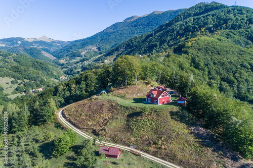 The house on a mountain of red color is surrounded by green trees. aerial view.