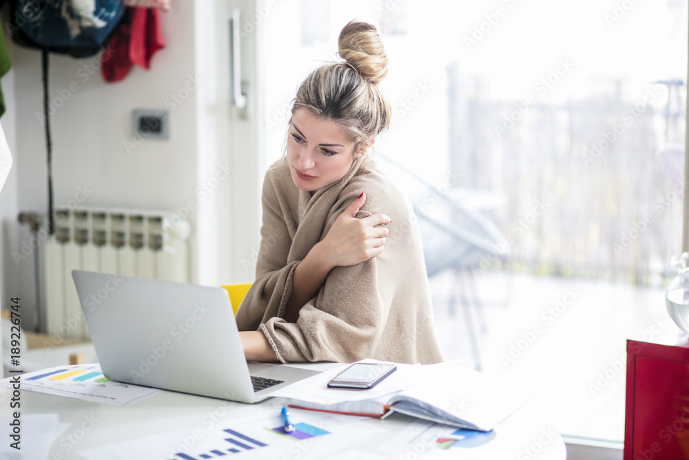 Young beautiful woman works on computer from a home with a laptop on a white desk as a freelancer.Self-employment concept