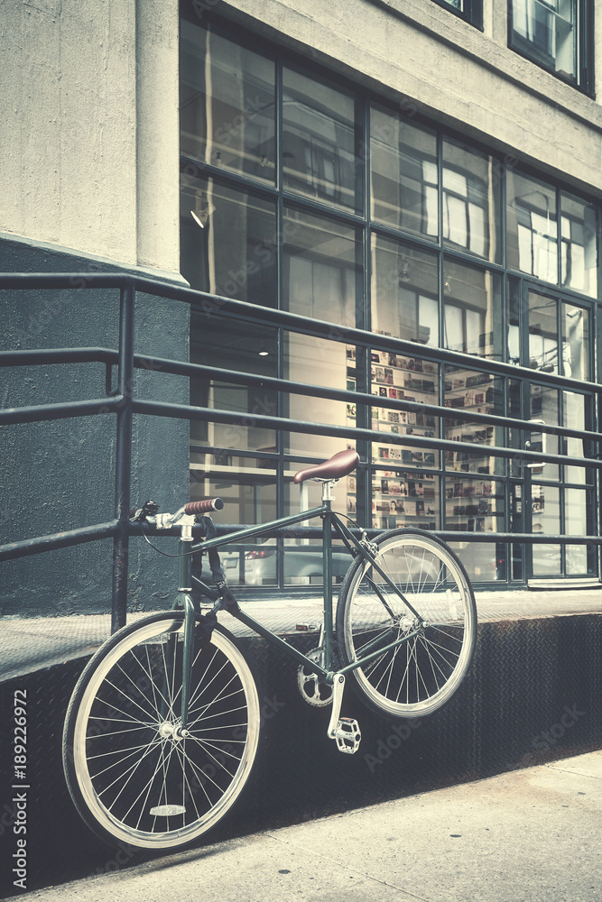 Retro stylized picture of a hanging bike by a street, New York City, USA.