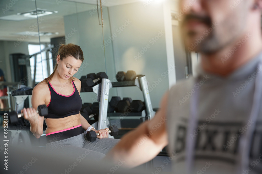 Athletic girl in fitness room lifting weight Athletic girl in fitness room lifting weight