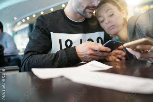 Young couple at the airport connected with smartphones