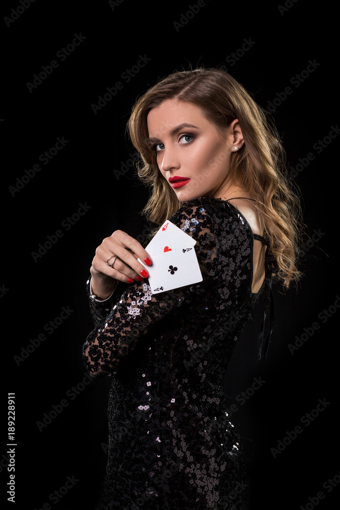 Young woman holding playing cards against a black background Young woman holding playing cards against a black background