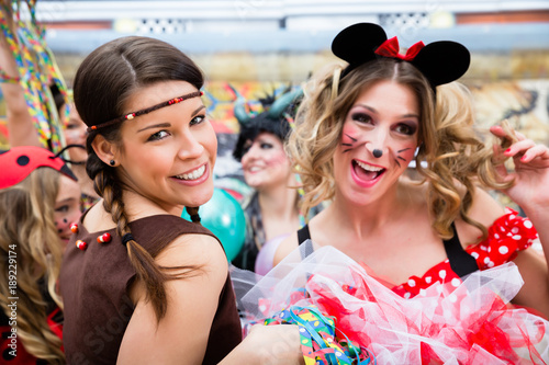 Junge Frauen an Karneval in Kostümen hauchen einen Luftkuss