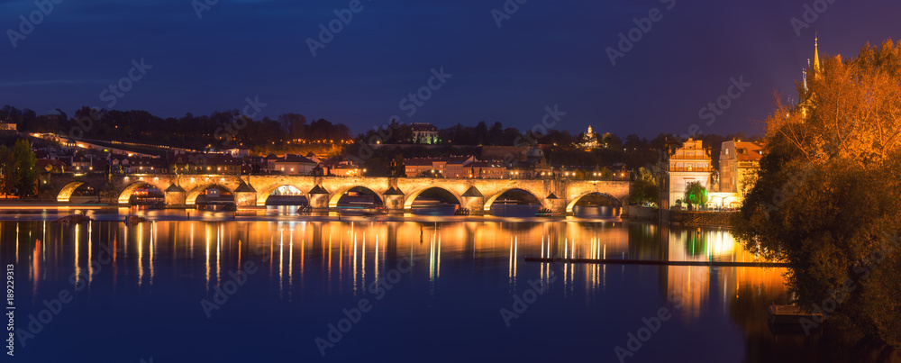 Large panorama of Prague, view of illuminated Charles bridge (Karluv most) with reflection in the water, night scenic cityscape, world famous historical heritage of Czech Republic