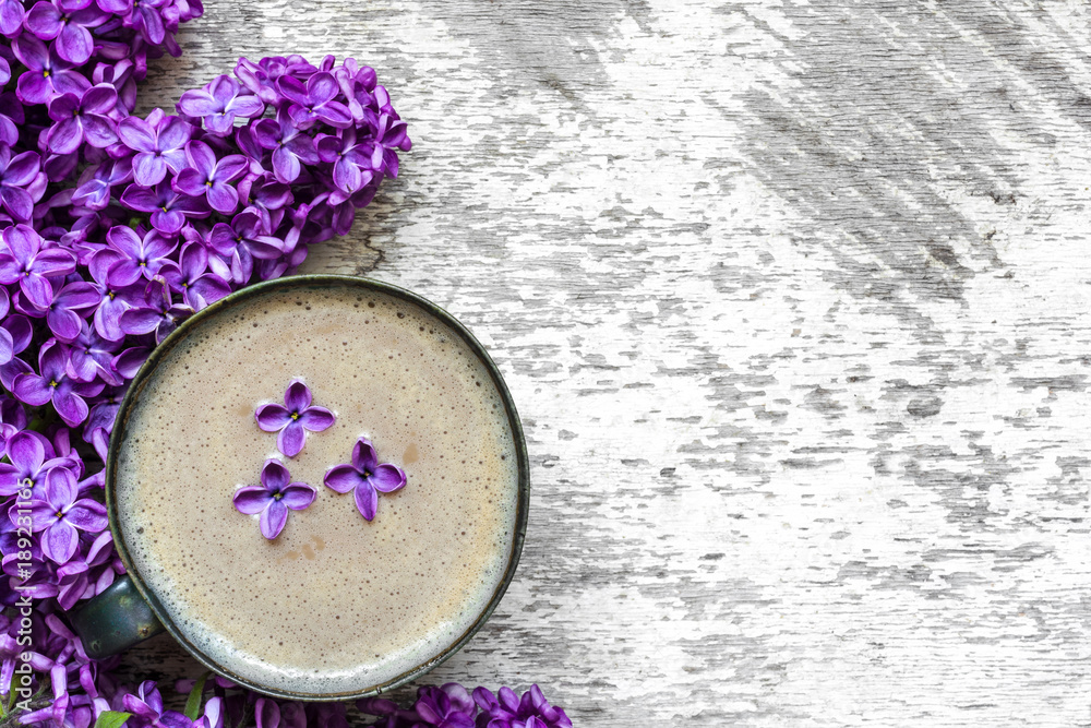 Cup of coffee with coffee and lilac flowers over rustic wooden background Cup of coffee with coffee and lilac flowers over rustic wooden background