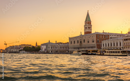 Gondola ride through the busy canals of Venice, Italy during sunset, with St Mark's Square and the Bell Tower in the distance.