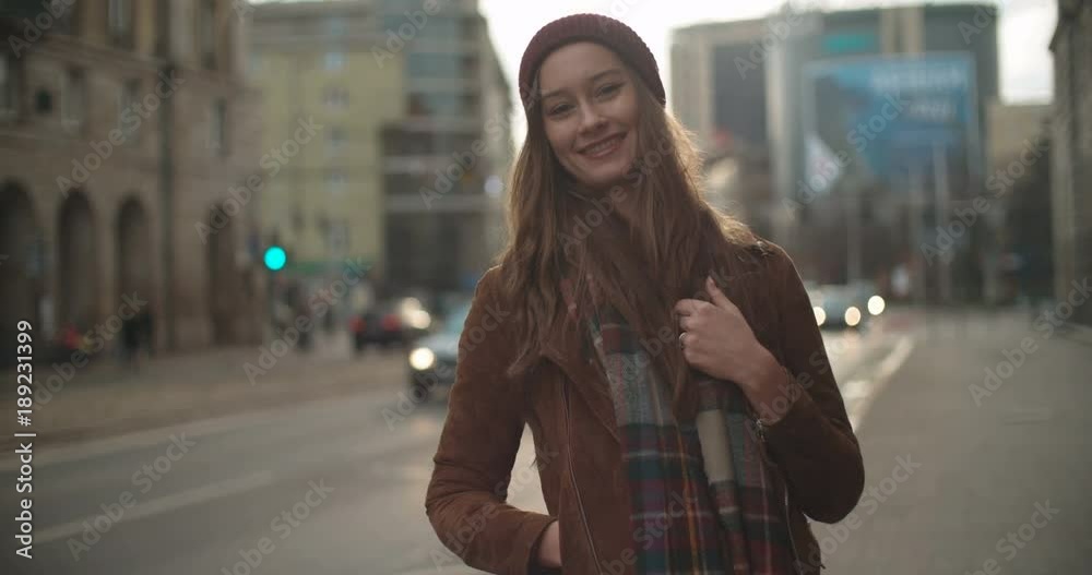 Portrait of beautiful youn woman standing in a city street and smiling to a camera. Portrait of beautiful youn woman standing in a city street and smiling to a camera.