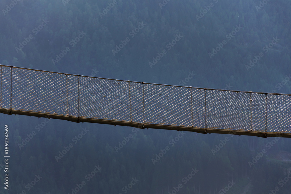 Steel rope suspension bridge on Alpine trail through Hell gorge canyon with Riesach waterfalls from lake Riesachsee near Schladming, Austria Steel rope suspension bridge on Alpine trail through Hell gorge canyon with Riesach waterfalls from lake Riesachsee near Schladming, Austria