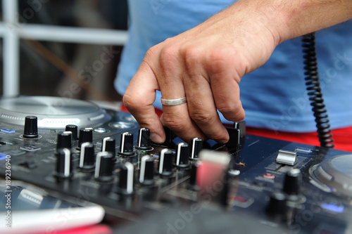 The DJ's hands on the mixing console adjust the parameters