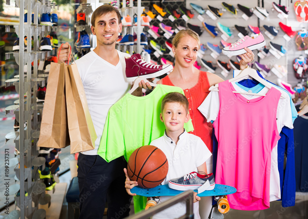 Couple with boy choosing shoes in sport shop
