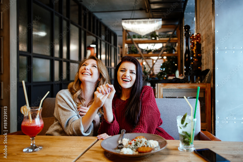 communication and friendship concept - smiling young women with nonalcoholic cocktails at cafe. two girlfriends blonde and brunette talk, joke and laugh communication and friendship concept - smiling young women with nonalcoholic cocktails at cafe. two girlfriends blonde and brunette talk, joke and laugh