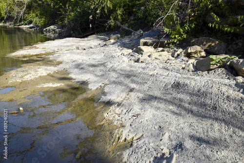 The mountain river. Shallow mountain river, water flows through the rocks. Rocks in the river water. Stones and layers of sedimentary rocks photo