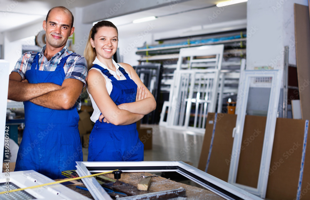 Obraz premium Man and woman in blue overalls standing with hands crossed at workplace