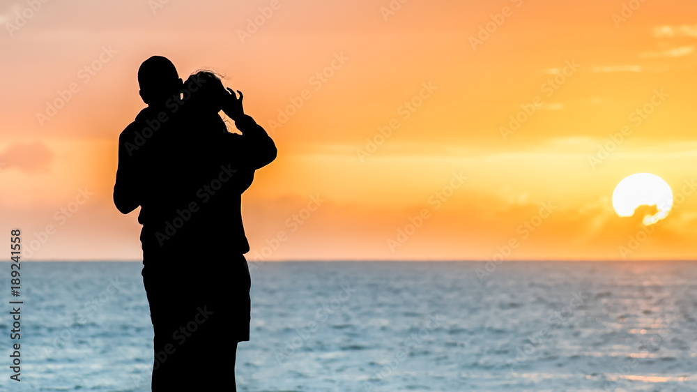 Silhouette eines Paares am Strand vor farbenprächtigen Sonnenaufgang