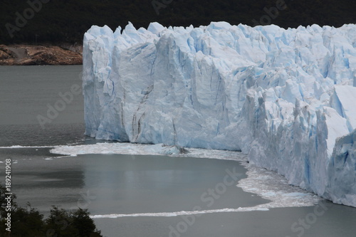 poszarpana struktura argentyńskiego lodowca schodzacego do wody z odłamującymi się bryłami lodu w pochmurny dzień © KOLA  STUDIO