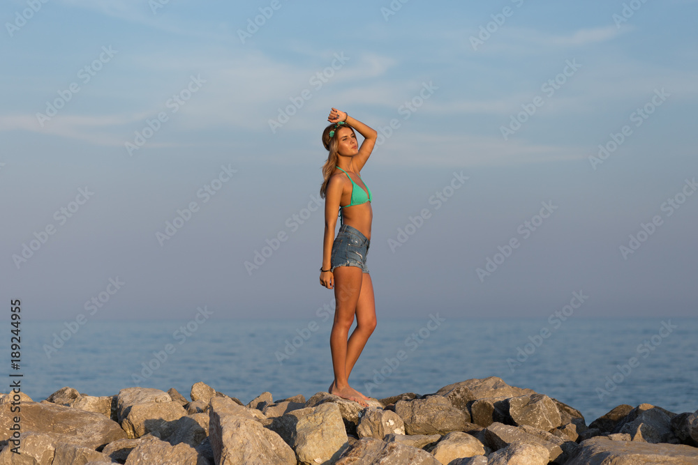 Junge schlanke Frau steht am Strand und schaut in die Ferne Junge schlanke Frau steht am Strand und schaut in die Ferne