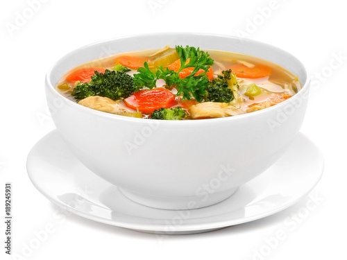 Homemade chicken vegetable soup in a white bowl with saucer. Side view isolated on a white background.