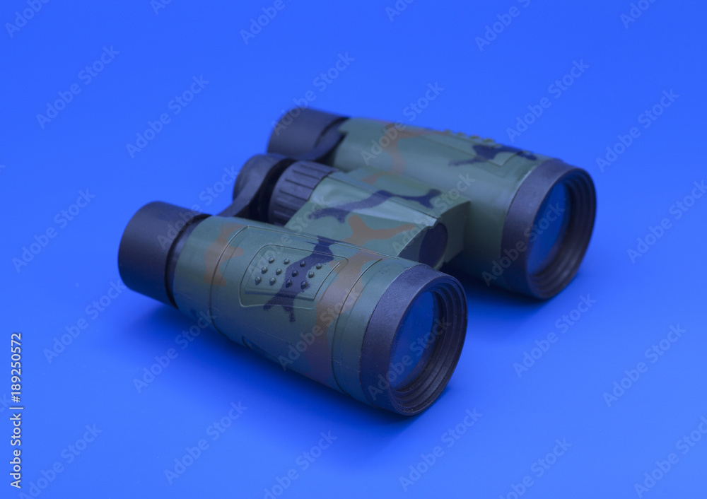 Camouflage binoculars on blue background