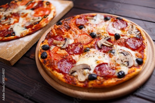 Delicious freshly baked pizzas close up on the wooden board, Italian food, restaurant concept