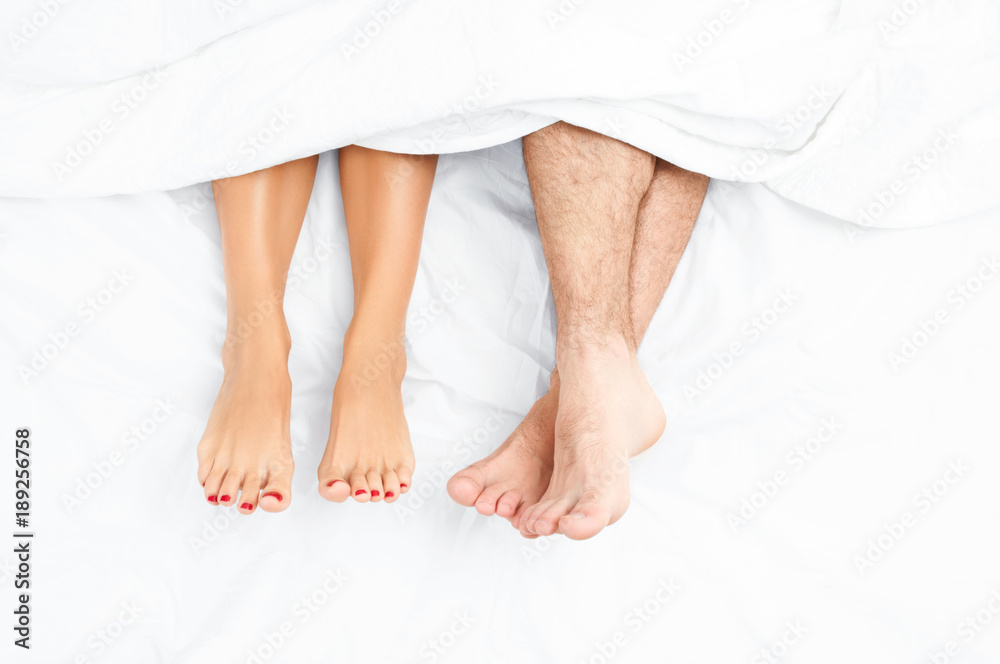 Close up of the feet of a couple on the bed.