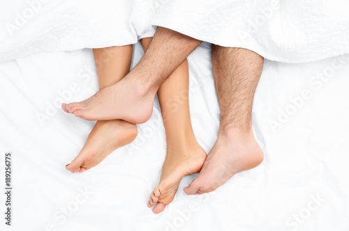 Close up of the feet of a couple on the bed.