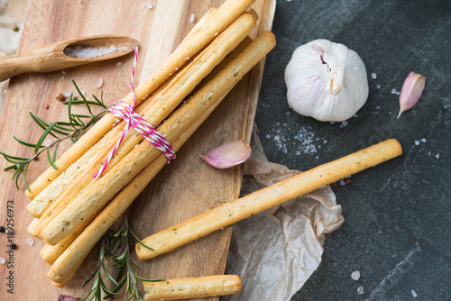 bread grissini with garlic and rosemary, sprinkled with salt on a stone table photo