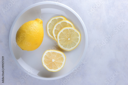 Slices of lemon in a minimalist style on a marble background, lemon on a white plate, healthy food, vegan, pop art, yellow lemons on a white background