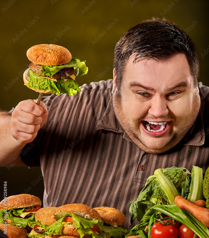 Fat man eating fast food hamberger. Breakfast for overweight person. Junk  meal leads to obesity. Person regularly overeats concept on green background.  Unhealthy food processing eating. Stock Photo | Adobe Stock