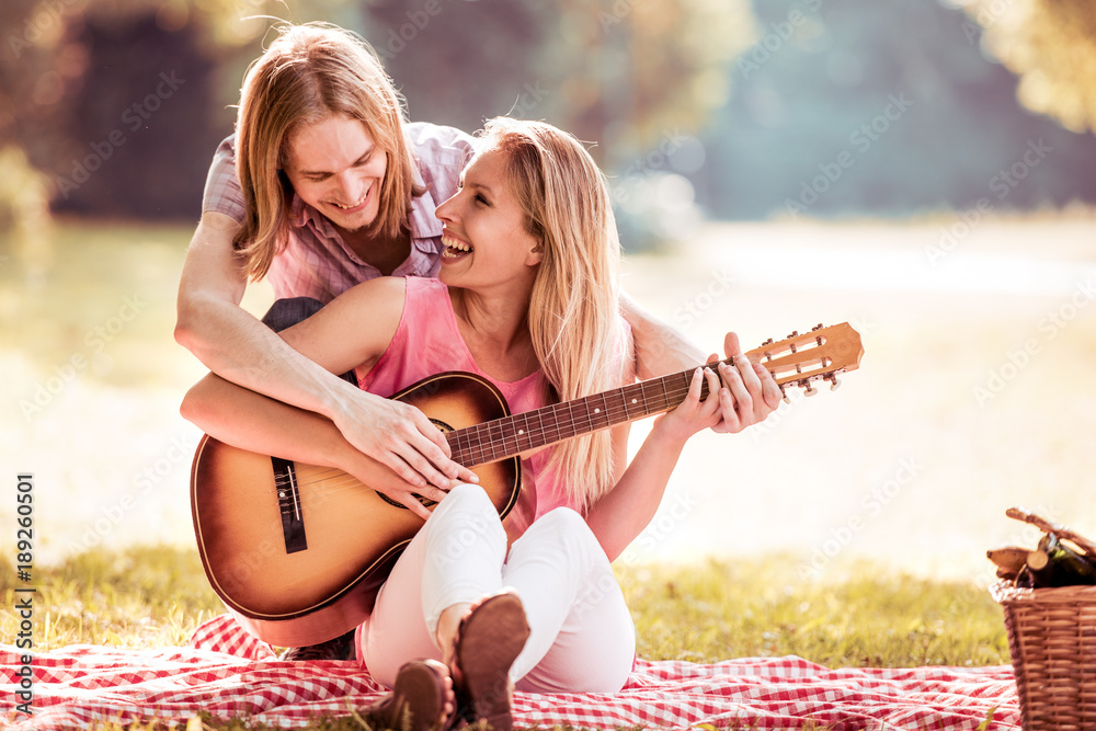 Young woman plays the guitar her boyfriend.