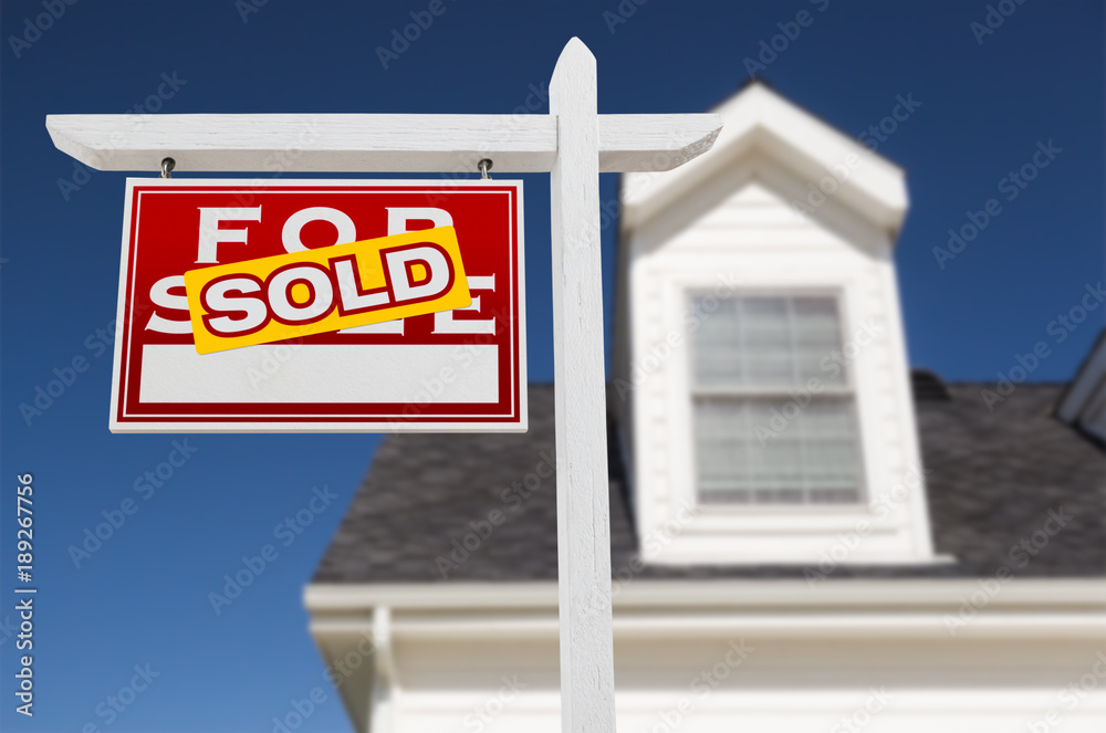 Left Facing Sold For Sale Real Estate Sign In Front of House and Deep Blue Sky. Left Facing Sold For Sale Real Estate Sign In Front of House and Deep Blue Sky.