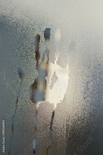 Fototapeta Naklejka Na Ścianę i Meble -  Wet window glass with hand shape print on natural abstract background. Close up picture textured foggy condensation surface